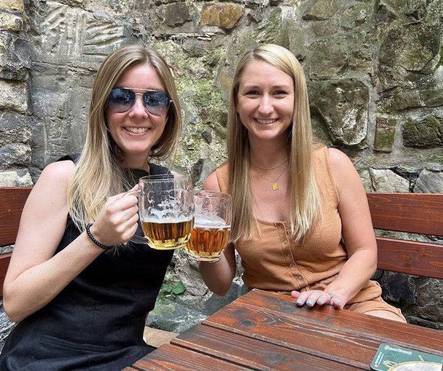 Two women holding beer mugs in Prague.