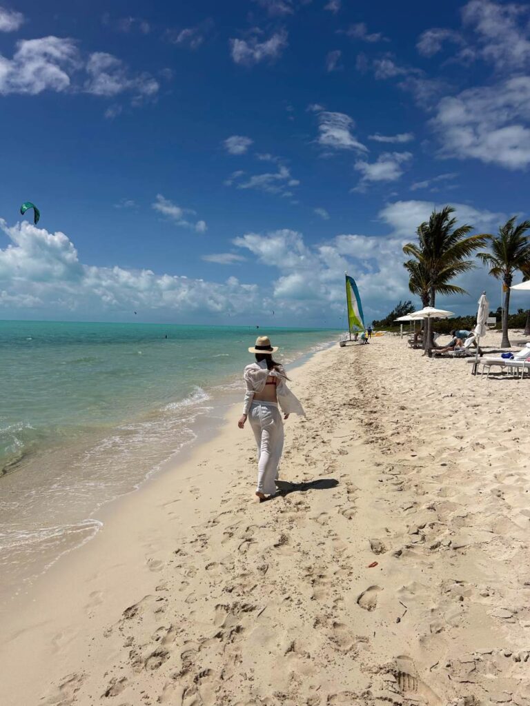 A woman walking on the white sandy shore of the Long Bay Beach, Turks and Caicos