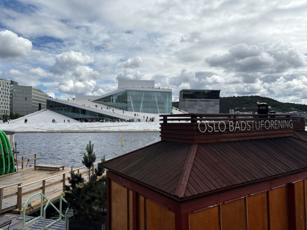 Visitors walking across the roof of the Oslo Opera House with panoramic city and fjord views.