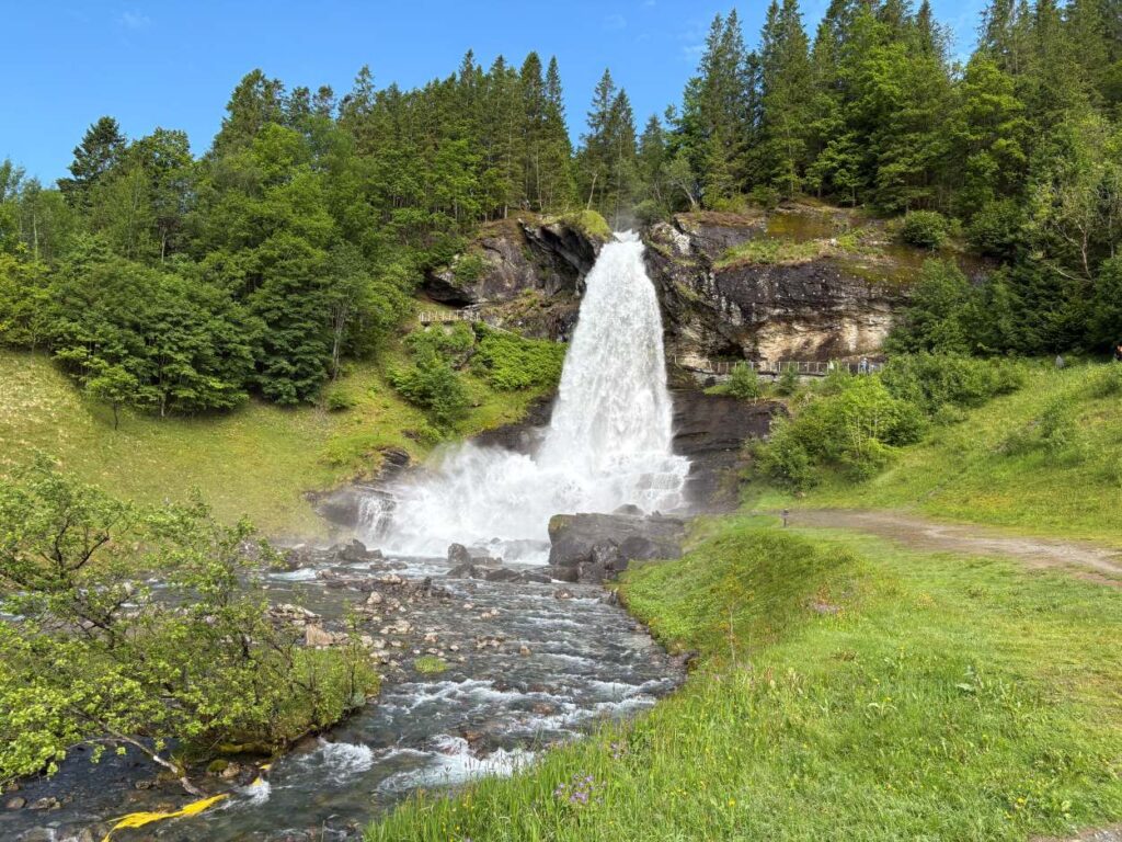 Majestic waterfall cascading into a Norwegian fjord surrounded by towering mountains