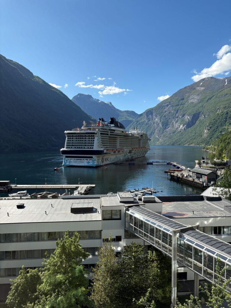 Panoramic view of Geirangerfjord surrounded by towering mountains and cascading waterfalls