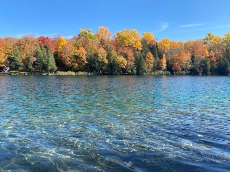 Vibrant autumn leaves surrounding the turquoise waters of Green Lakes State Park.
