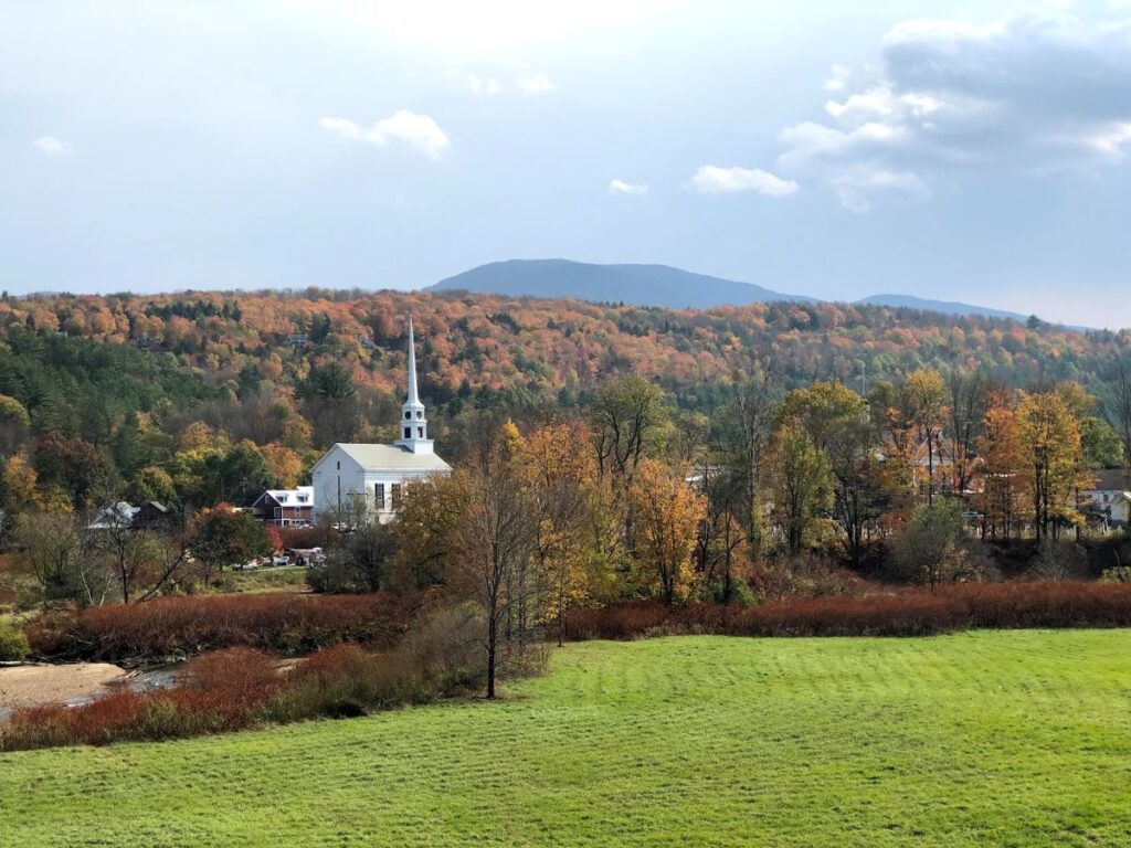 Scenic Stowe streets lined with vibrant fall trees and mountain views during Vermont in Fall