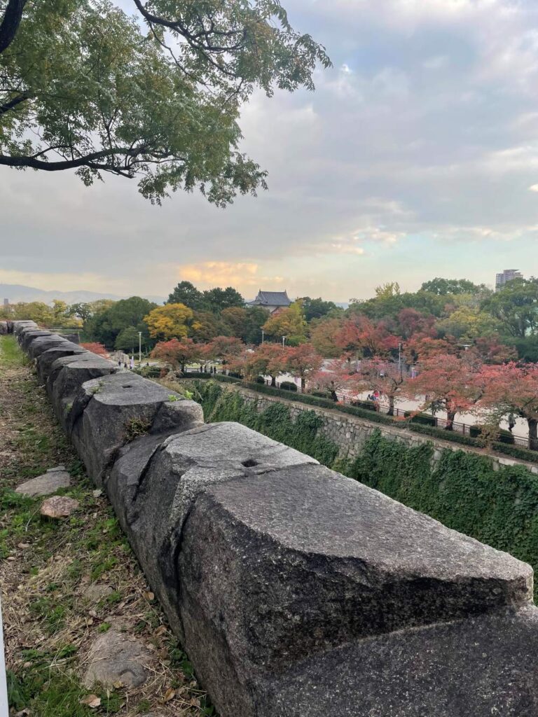 Osaka Castle rising above the trees in Osaka, Japan, with its traditional architecture and golden rooftop details