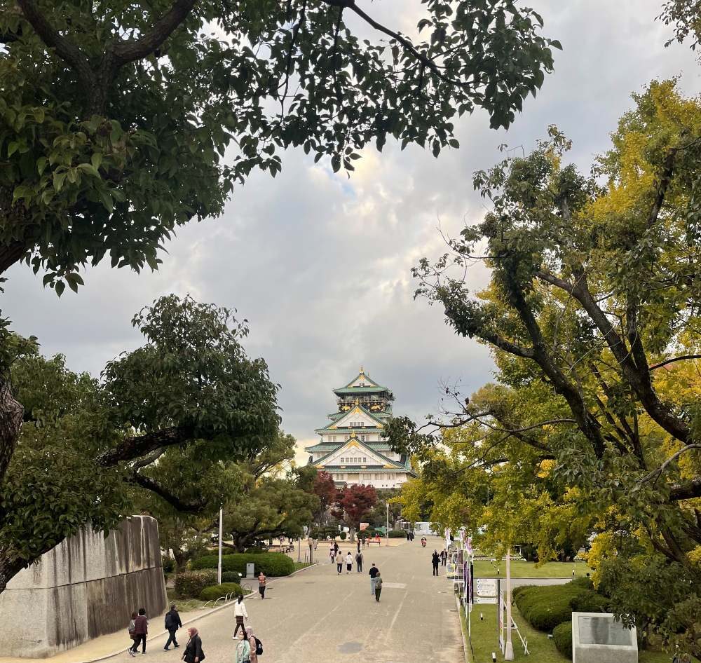 Osaka Castle surrounded by lush greenery and stone walls in Osaka, Japan, with its distinctive white and gold exterior