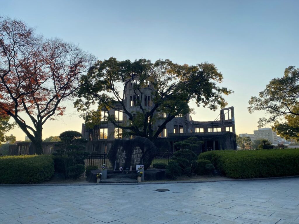 Hiroshima Peace Memorial Park in autumn with memorial monuments, trees, and visitors exploring the grounds